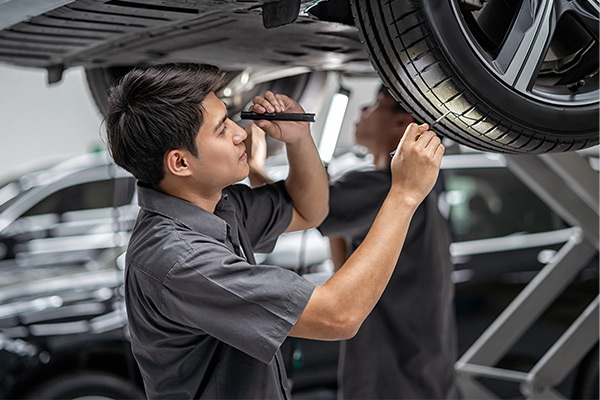 Mechanic in uniform is working in auto service. Car repair and maintenance.