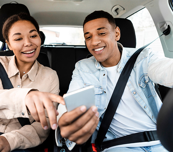 Couple inside of car looking car looking at phone