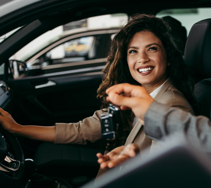 Woman in drivers seat of car being handed car keys