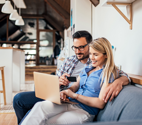 Couple shopping online while sitting on the sofa in modern apartment.