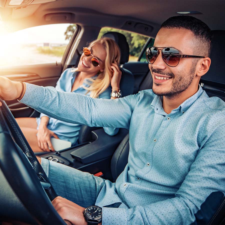 Man driving car with smiling woman passenger.