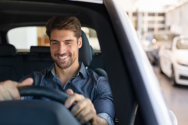 Man smiling in seat of car in dealership