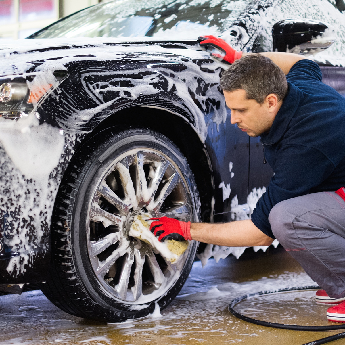 Man washing rims on car tires.