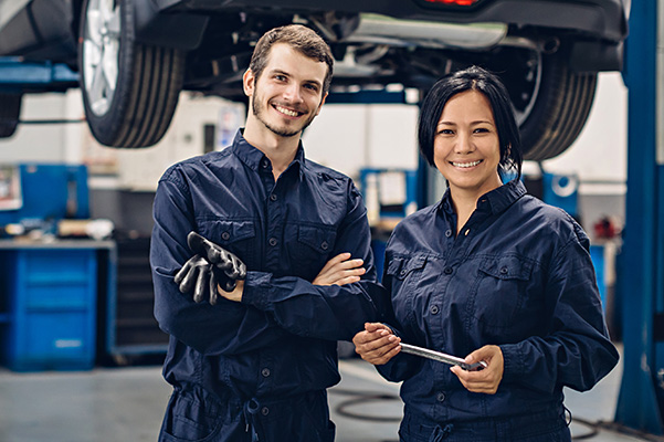 Auto technicians posing in front of a car in the service bay