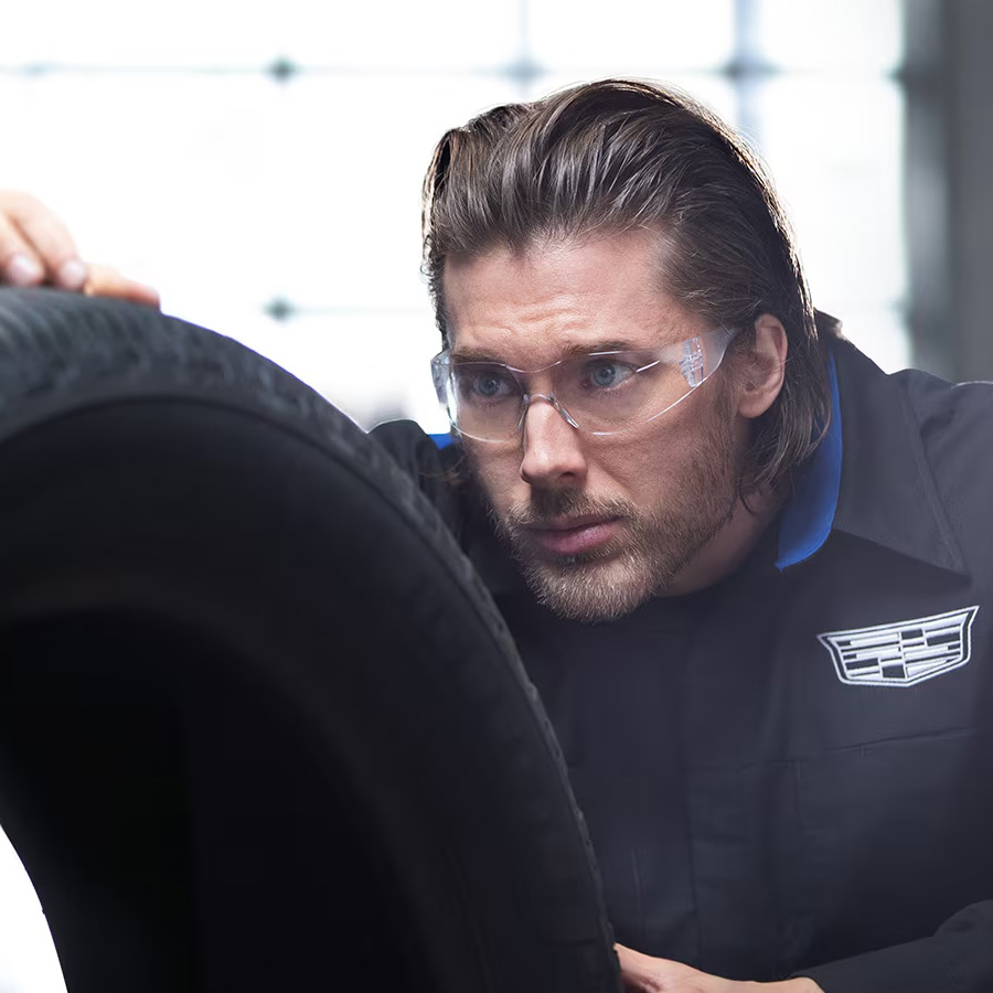 A Male Service Tech with Safety Glasses On Looking at the Tread of a Tire