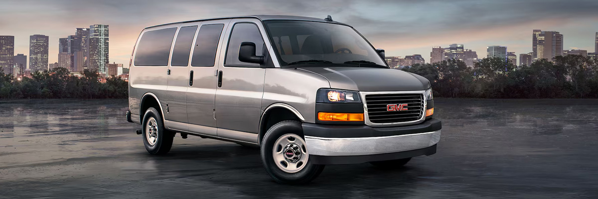 Wide Front Three-Quarters View of a 2025 GMC Savana Passenger Van with a City in the Background