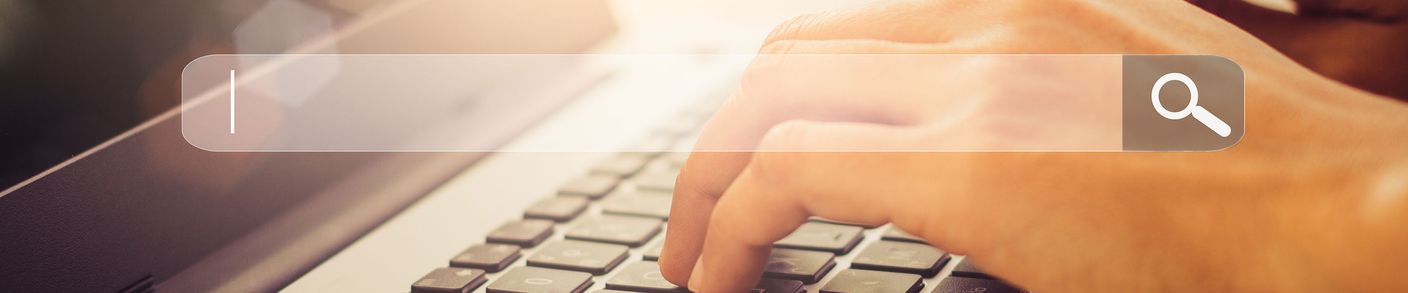Close up of hands on a laptop keyboard with a search bar overlayed on the image