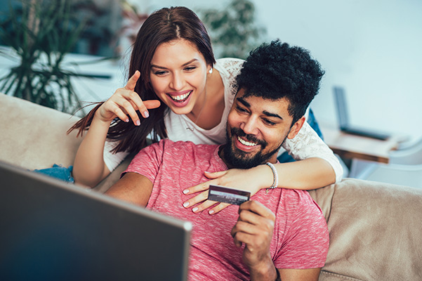 Two people smiling looking at credit card info for ordering online