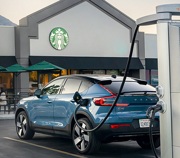 White electric car connected to power station charger on green background