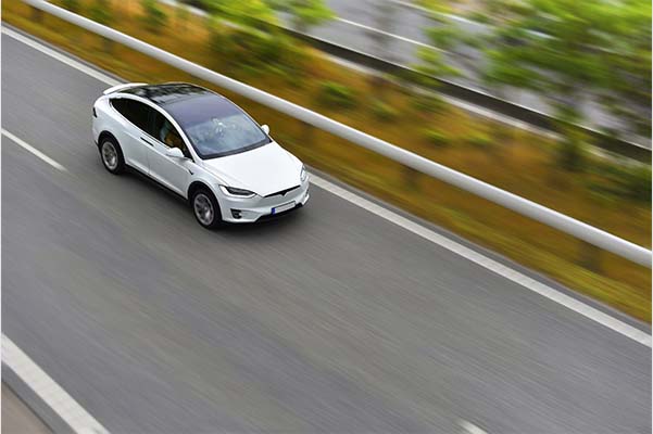 Modern electric crossover car is driving by highway on high speed