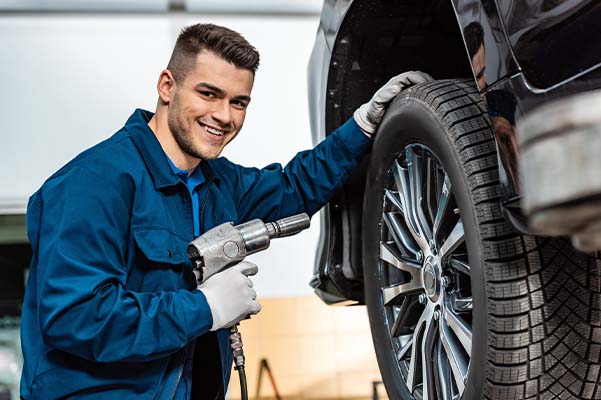 Cheerful mechanic looking at camera while holding pneumatic wrench
