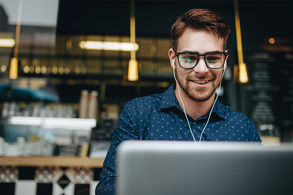 Customer smiling using laptop in coffee shop