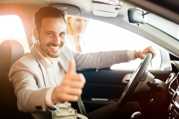 Customer smiling giving thumbs up in driver seat of car