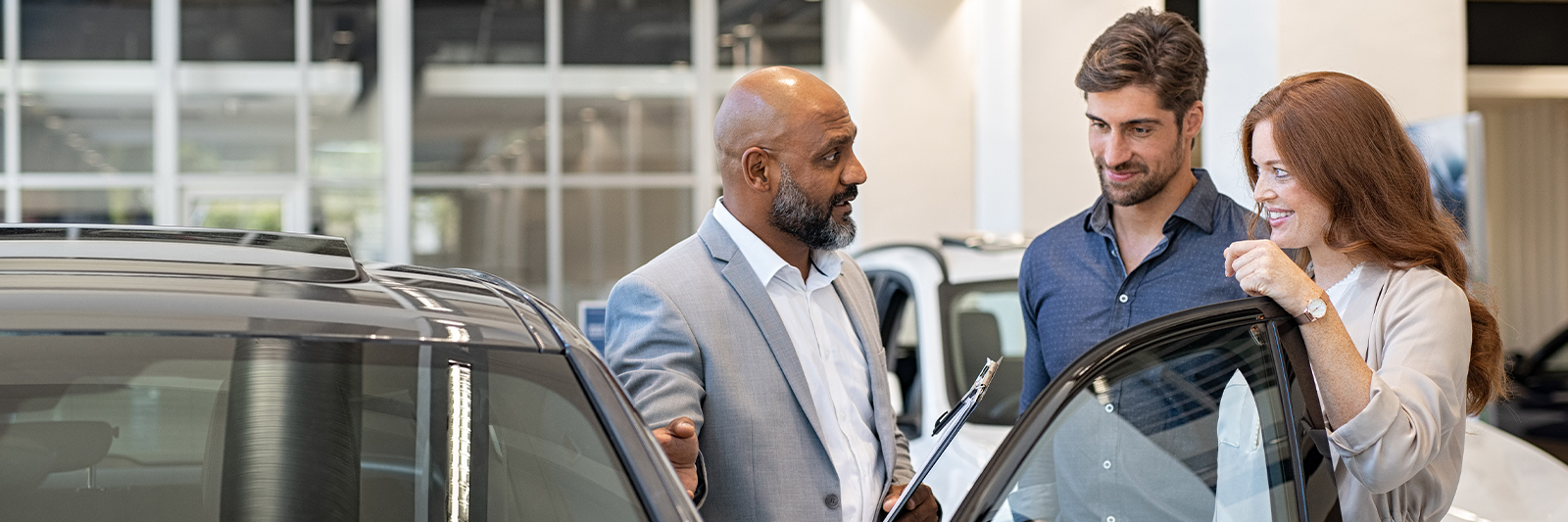 Dealership employee showing customers cars on showroom floor.