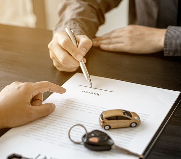 close up of someone signing a contract with car keys in sight