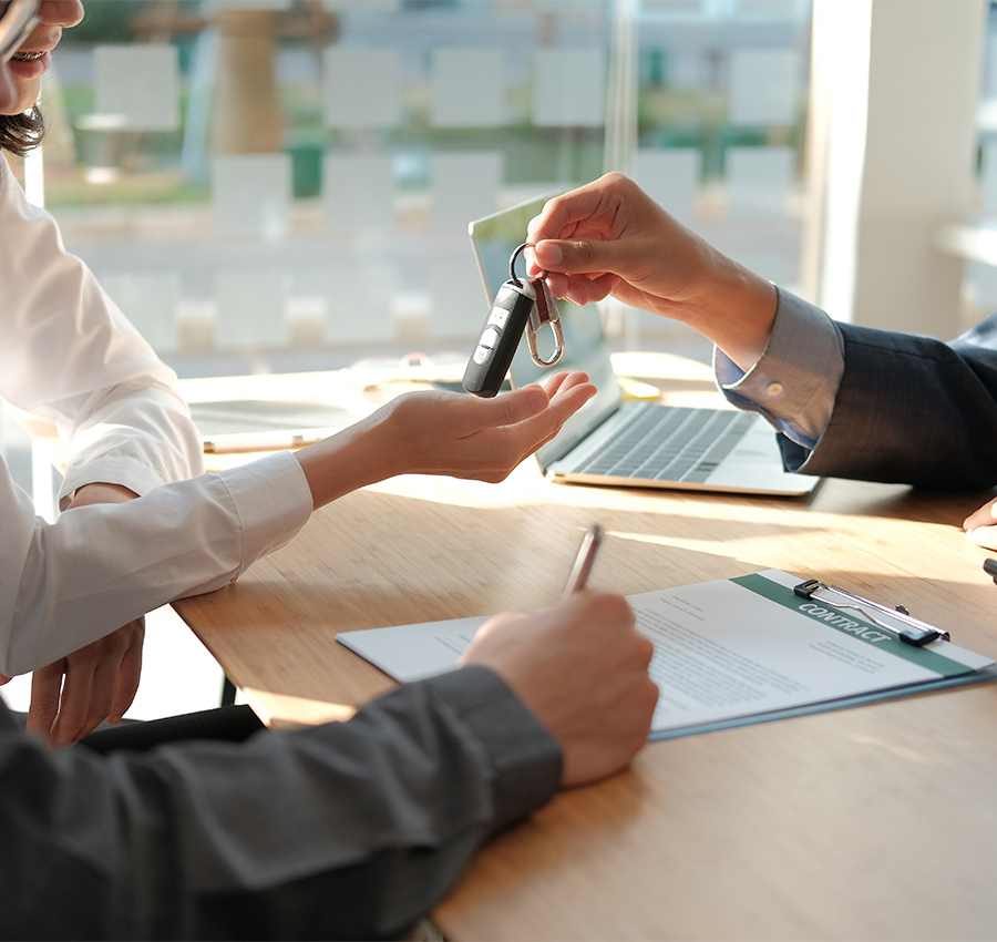 dealer salesman giving car key to owner. client signing insurance document or rental car lease form.