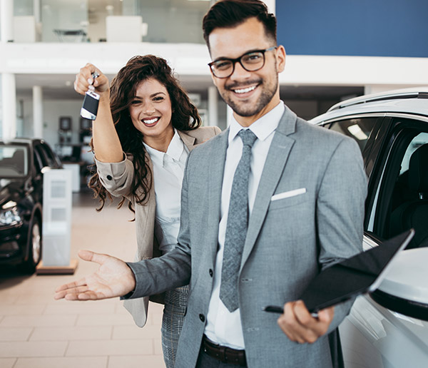 dealership employees holding out car keys 