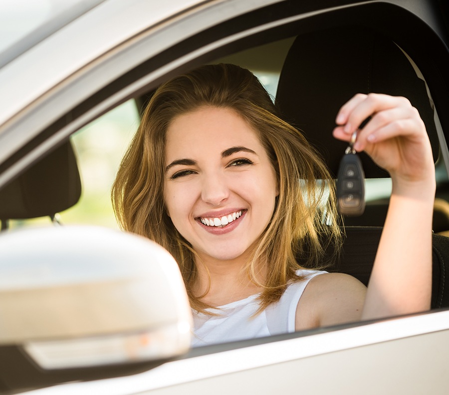 Woman smiling holding car keys to new car.