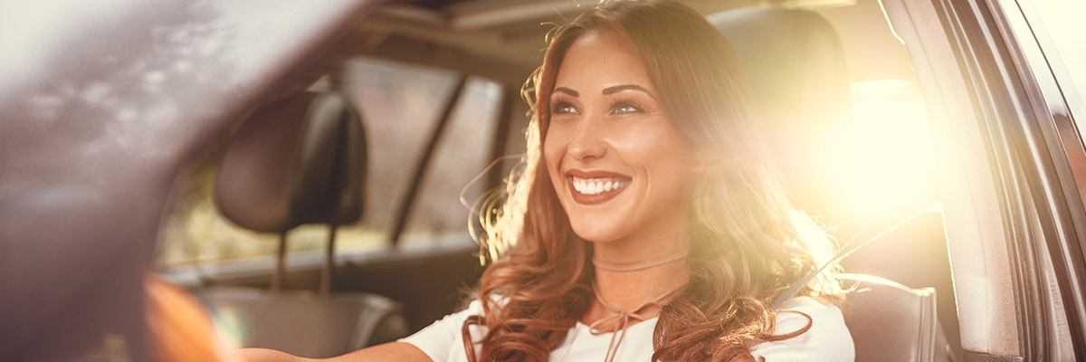 Happy woman smiling in drivers seat of car.