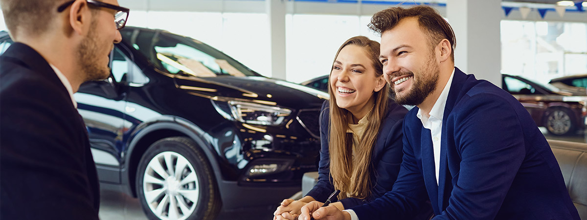 Couple smiling while talking with car salesman