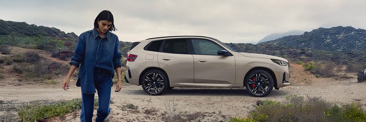 woman walking away from bmw parked in wilderness