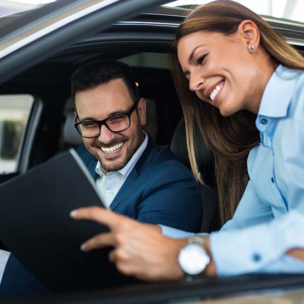 Customer in vehicle being shown information by dealership employee 