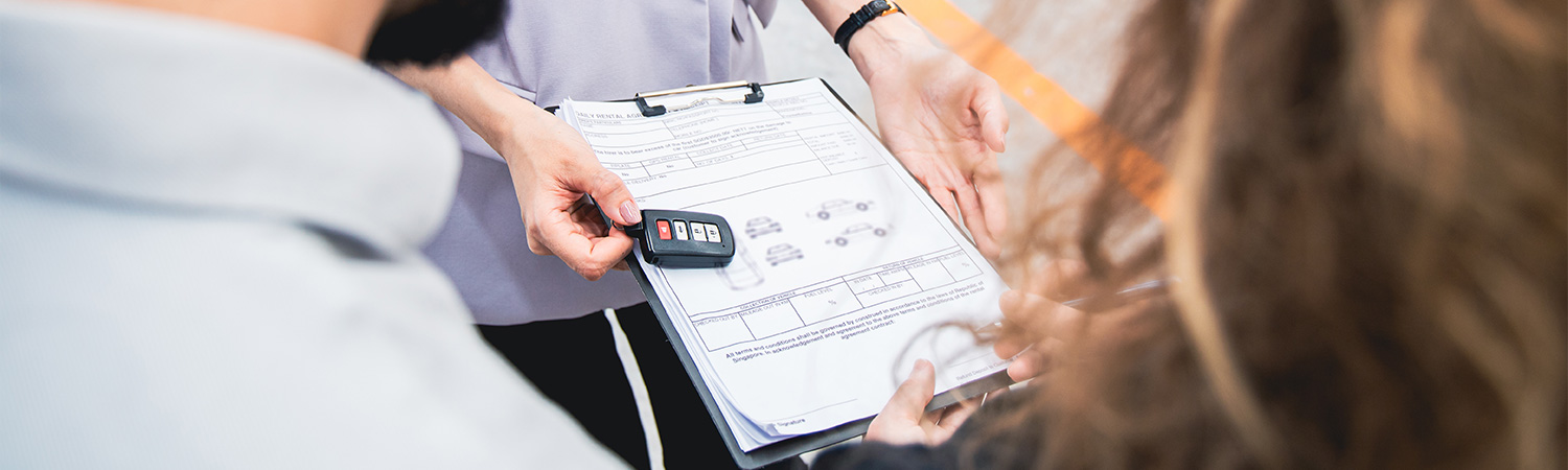 Car keys and papers being handed over on clipboard 