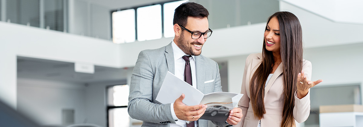 two people talking at a car dealership