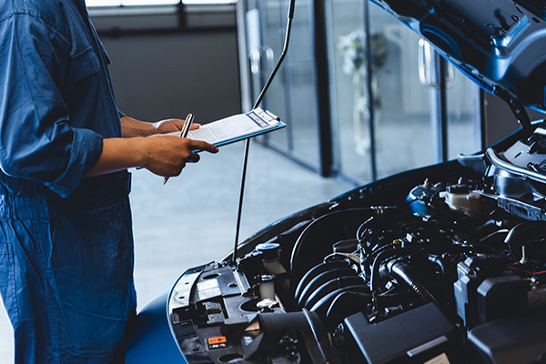 service person working under the hood of a car