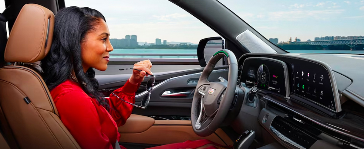 Woman driving a Cadillac with city shown in the background