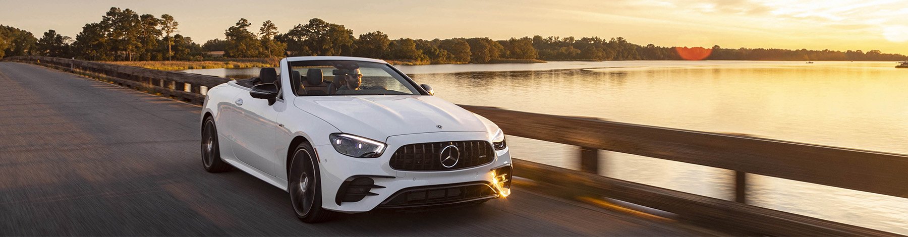 Mercedes-Benz convertible driving next to a lake