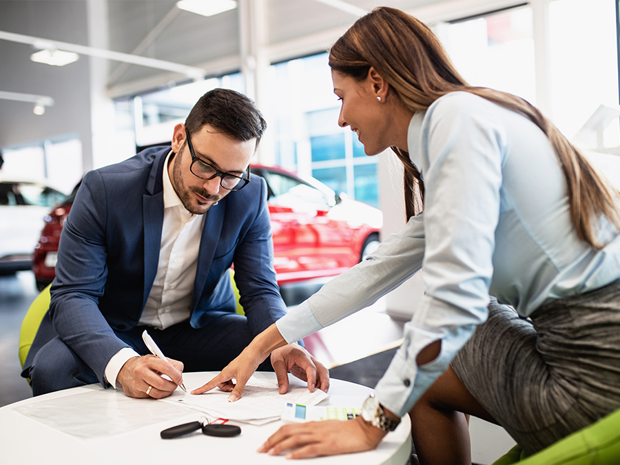 Dealership employee pointing to finance paperwork