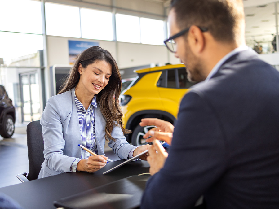 Dealership employee pointing to finance paperwork