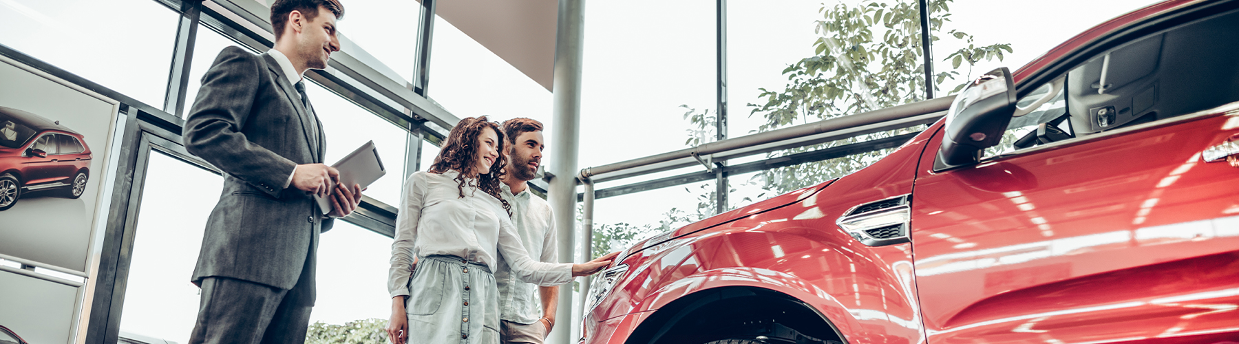 Dealership employee showing a couple a vehicle in the showroom