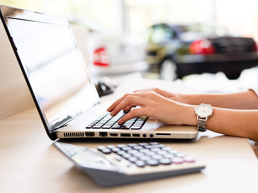 Person on their computer in the dealership with a calculator beside it