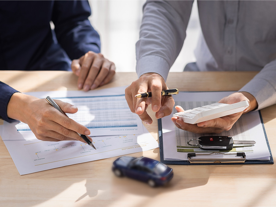 Person on their computer in the dealership with a calculator beside it