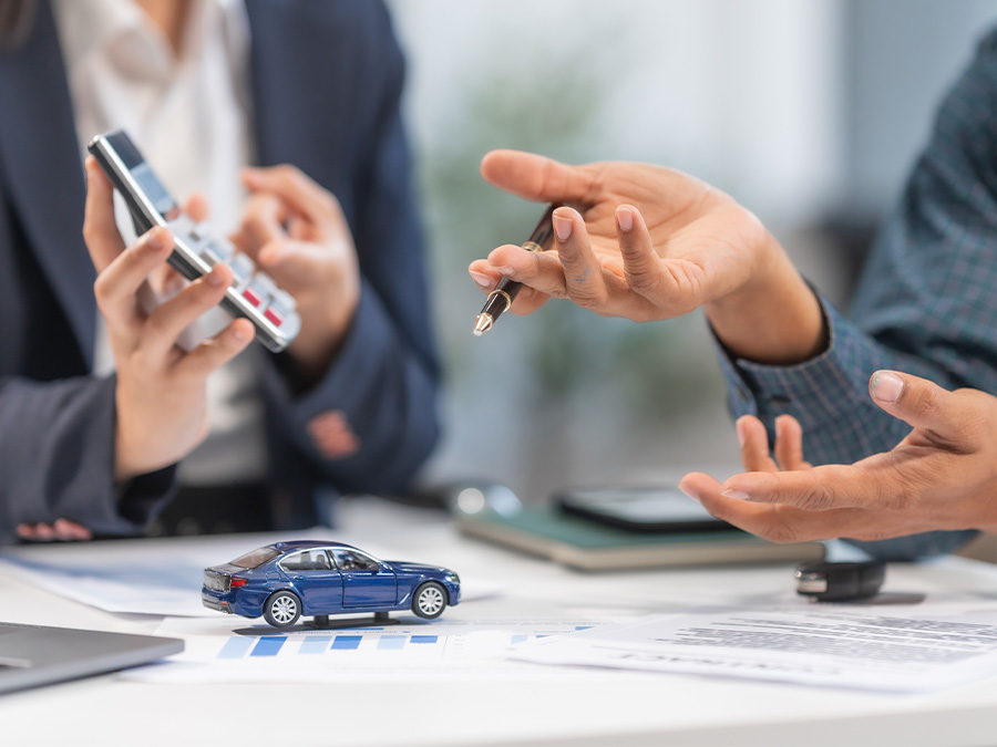 Person on their computer in the dealership with a calculator beside it