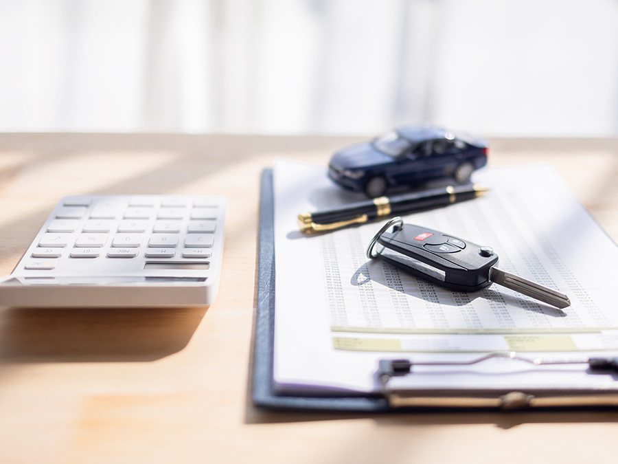 Person on their computer in the dealership with a calculator beside it