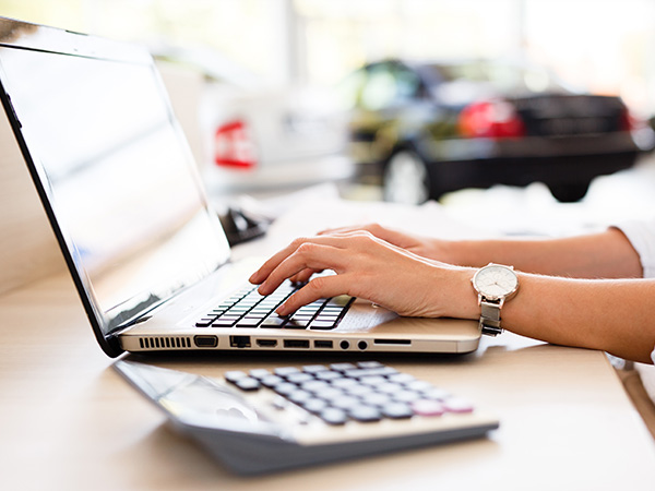 Person on their computer in the dealership with a calculator beside it