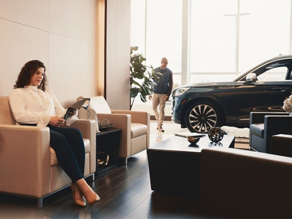 Dealership employee handing a clipboard to the customer with keys on it