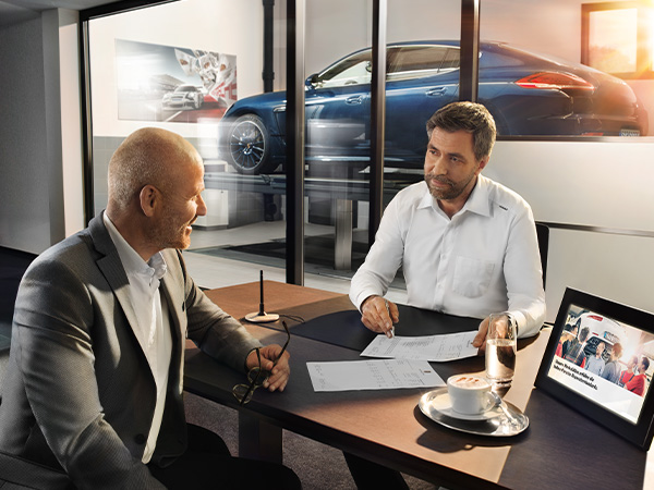 Dealership employee handing a clipboard to the customer with keys on it
