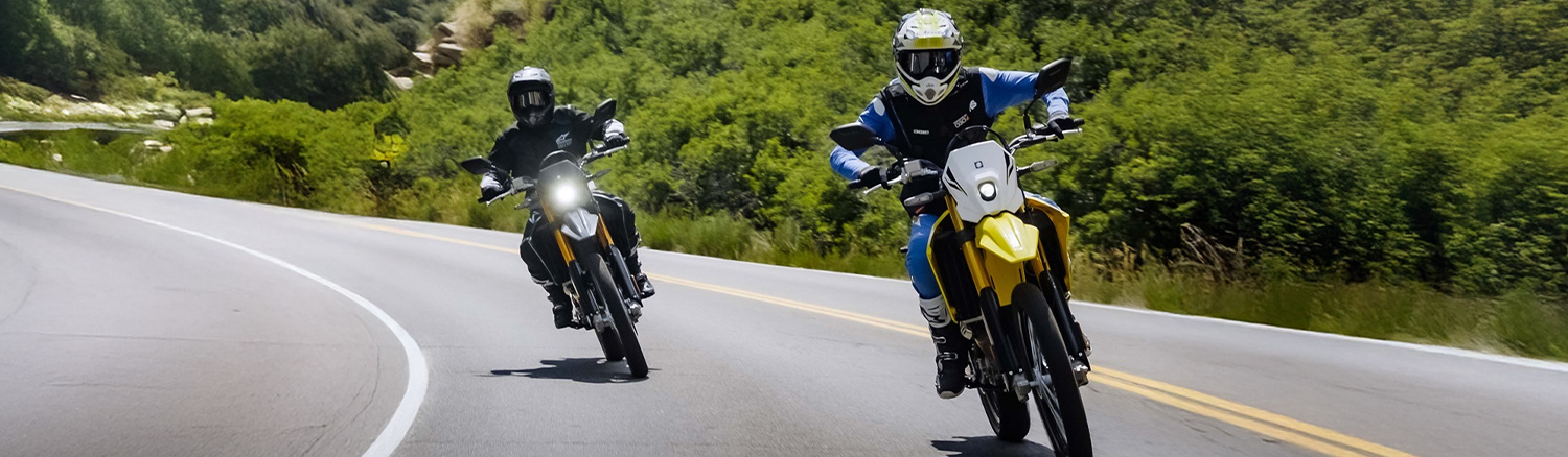 Two people riding down the road on a dirtbike