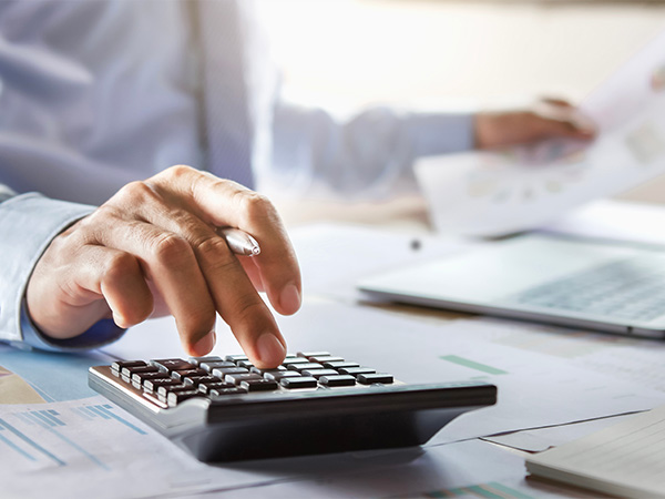 Person on their computer in the dealership with a calculator beside it