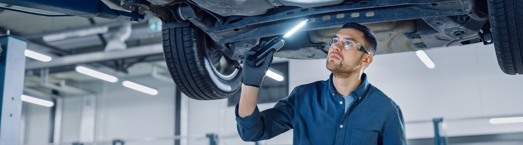 Service tech checking underneath a vehicle