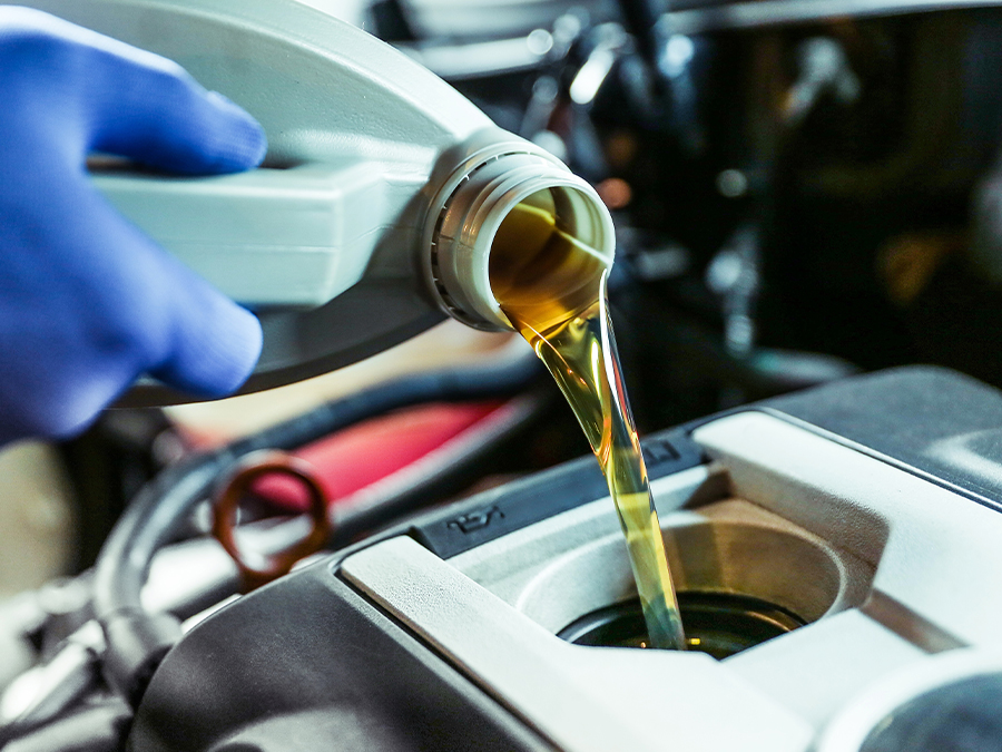 Service tech pouring oil into a vehicle for an oil change