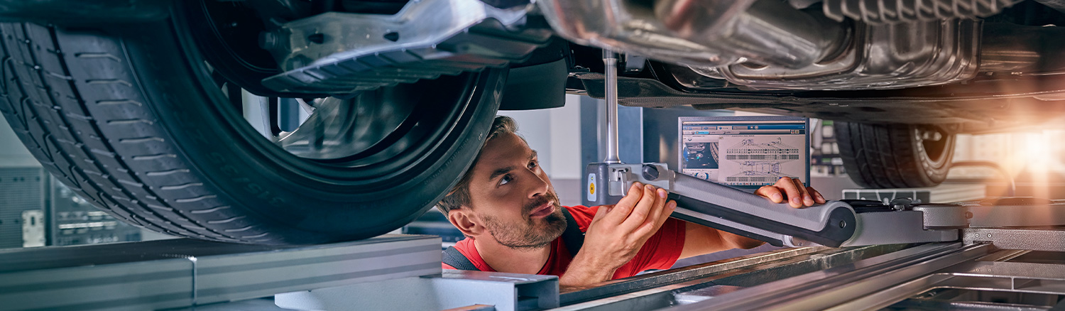 Service tech checking underneath a vehicle