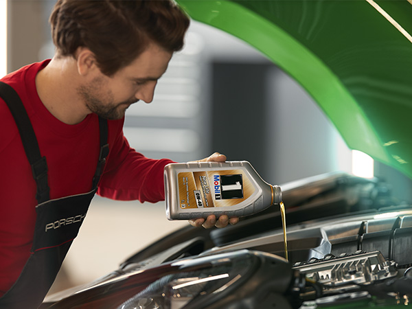 Service tech pouring oil into a vehicle for an oil change