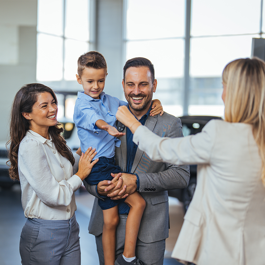 Dealership employee smiling shaking hands with satisfied customer.