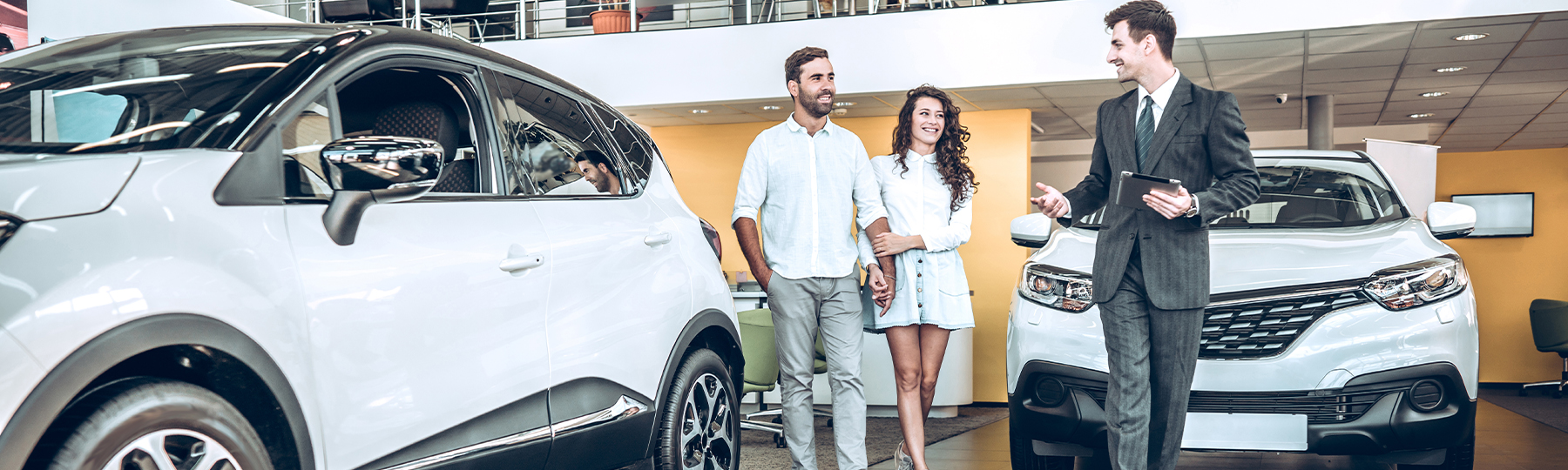Dealership employee showing customers cars on showroom floor.