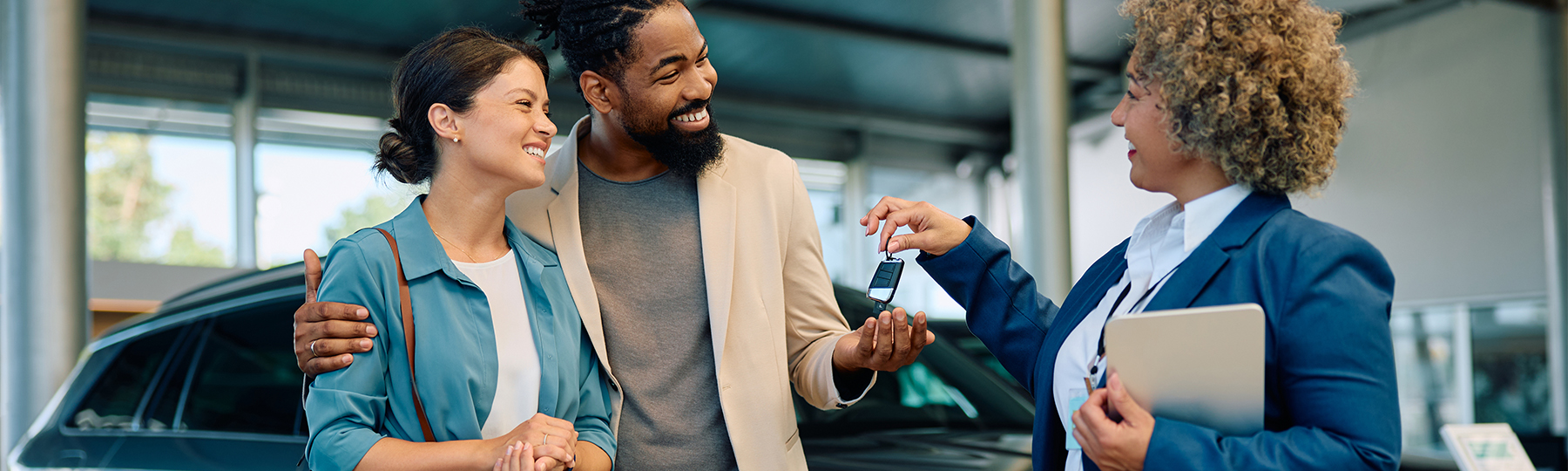 Dealership employee showing customers cars on showroom floor.